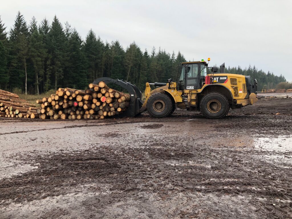 A loader fitted with an Ulrich Timber Handling Grapple. Grapple grabbing a number of logs.