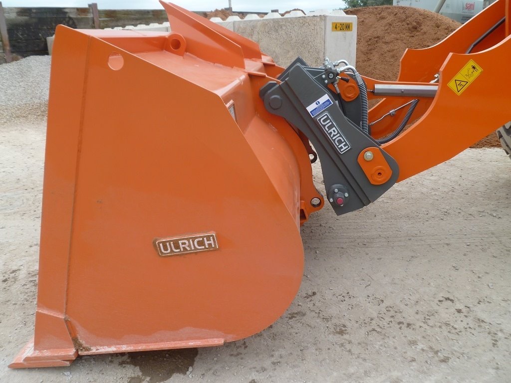 Grey Ulrich quick coupler attached to an Ulrich bucket.